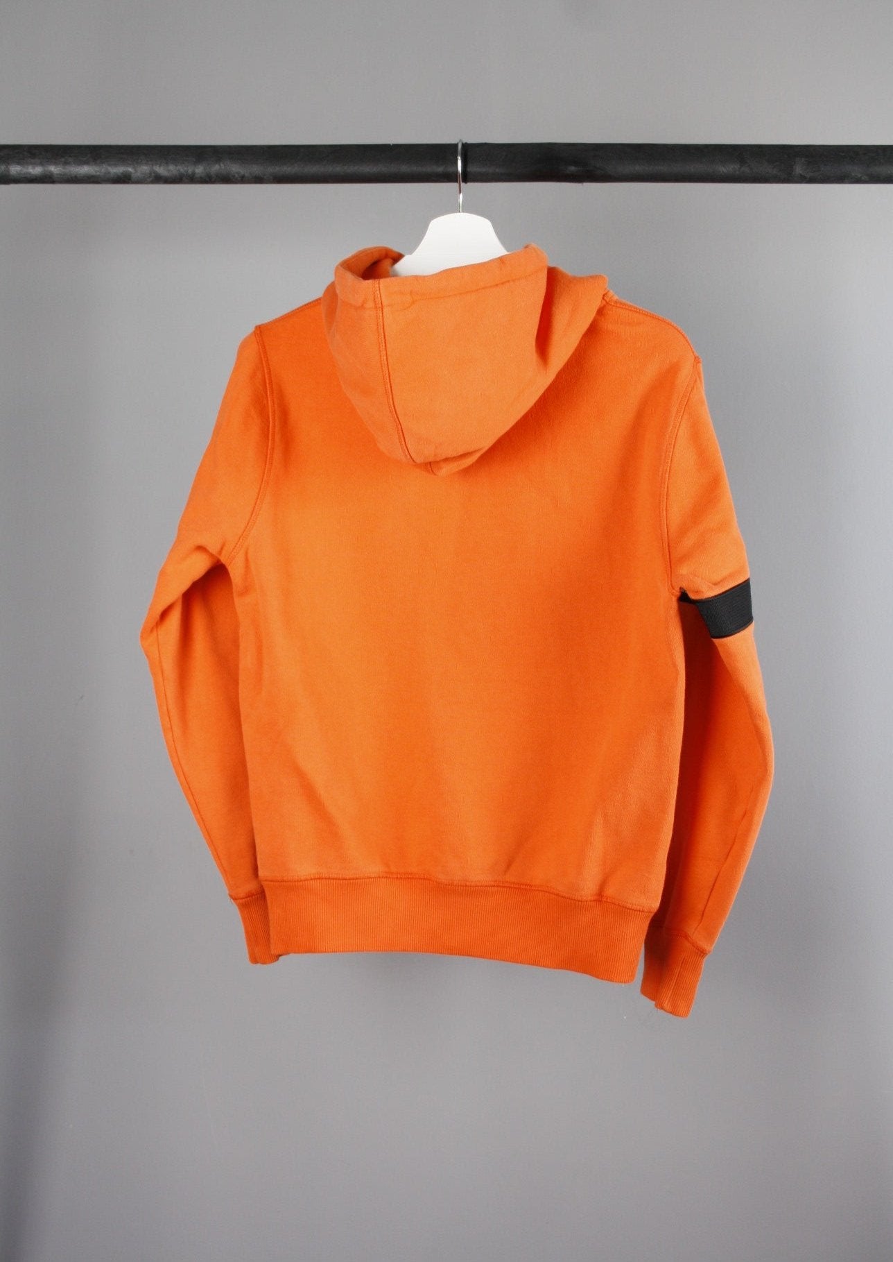 Achterkant van een oranje Daily Paper Captain hoodie met een zwarte band op de rechterarm, perfect voor een trendy en opvallende casual look.