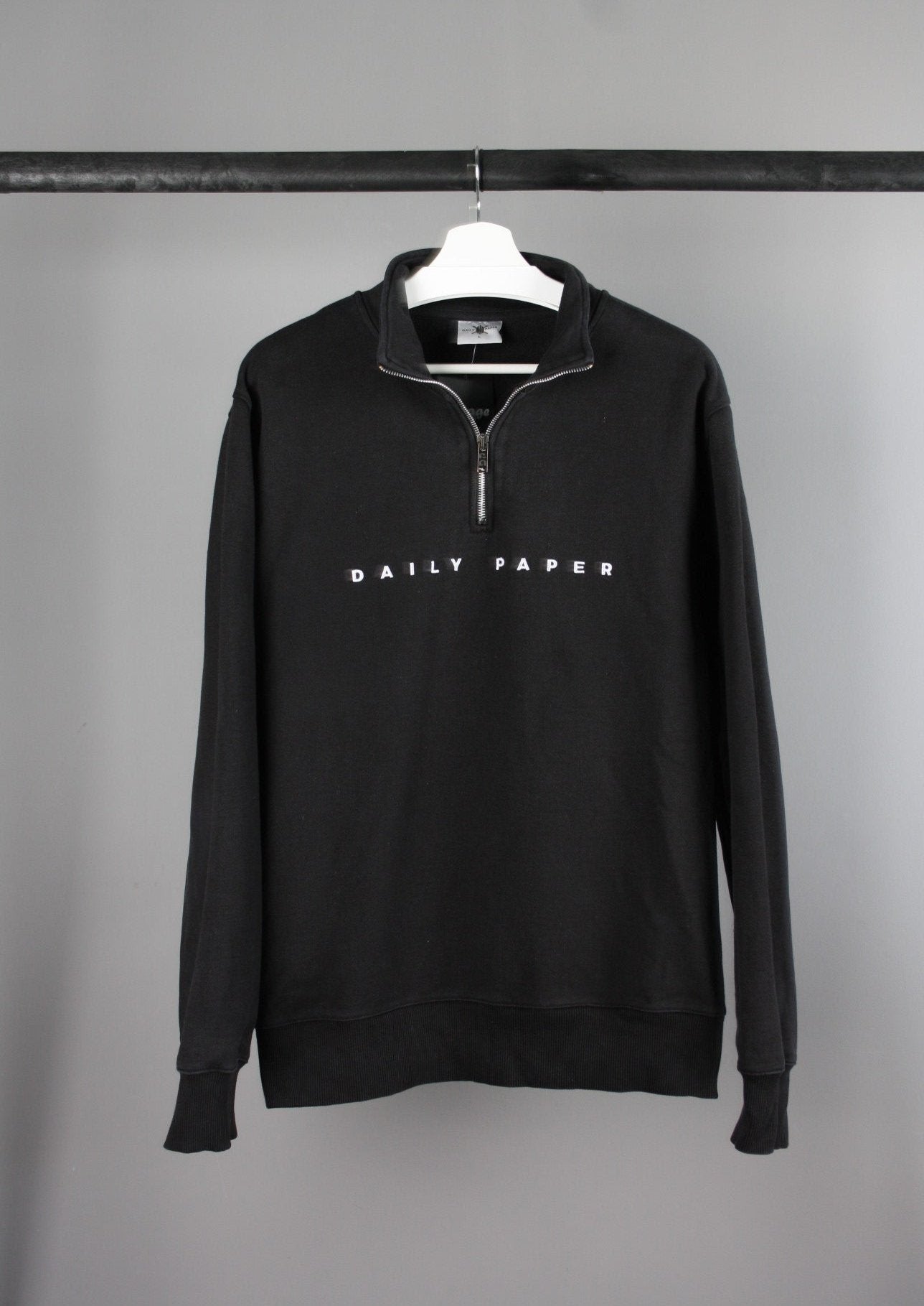 Voorkant van een Daily Paper quarter zip sweater met witte tekst op de borst, gemaakt van comfortabele stof met een moderne en minimalistische uitstraling.