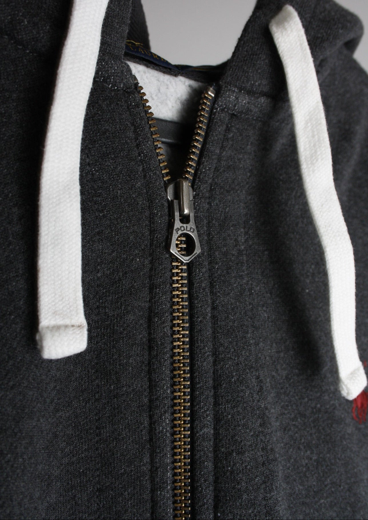 Close-up van de details van een donkergrijs Ralph Lauren vest, met zorgvuldig afgewerkte ritsen en knopen voor een luxe uitstraling.