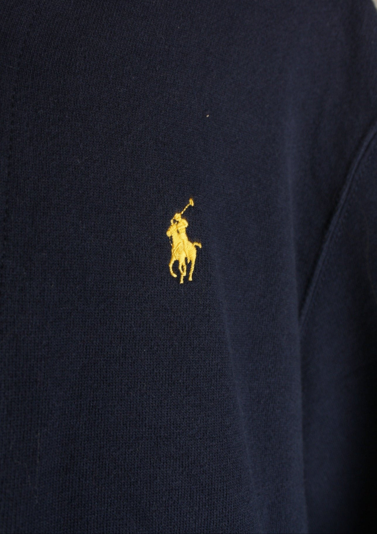 Close-up van het gele paardje op de voorkant van een marineblauw Ralph Lauren vest, het herkenbare logo van het merk.