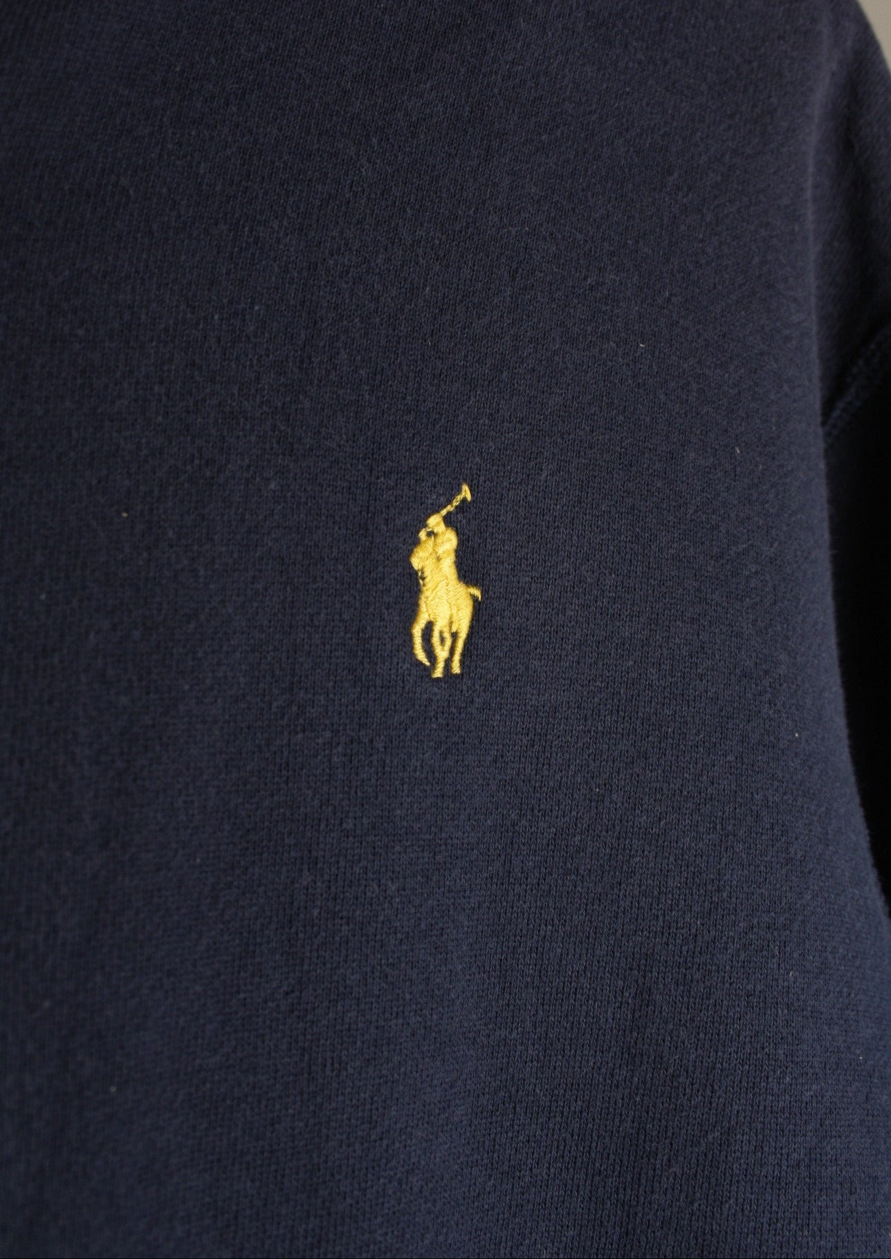 Close-up van het geel geborduurde paardje op de voorkant van een marineblauw Ralph Lauren vest in maat XL, het merkiconische logo.