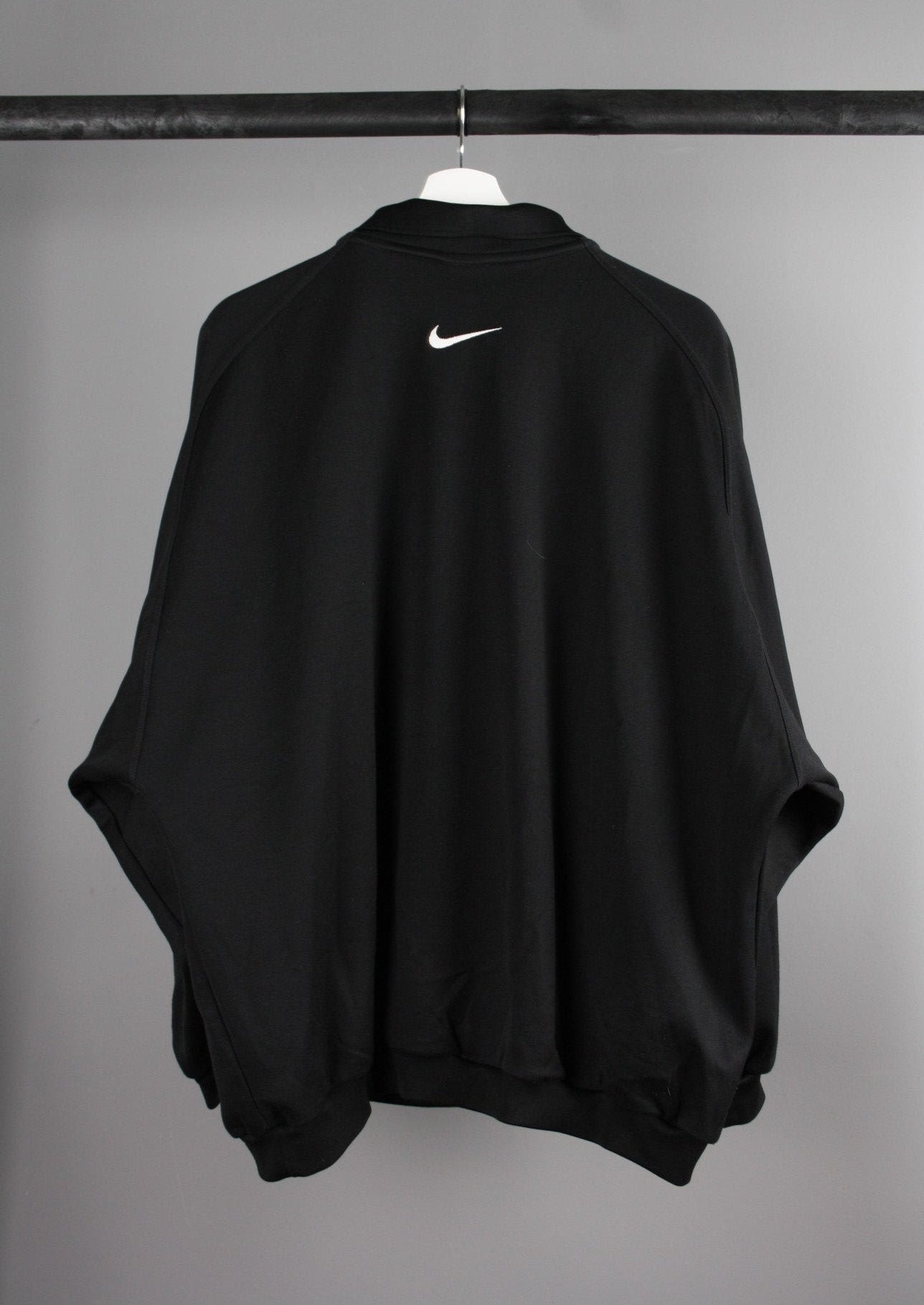 Achterkant van een zwarte Nike quarter-zip sweater met een minimalistische stijl en een comfortabele pasvorm, ideaal voor sportieve en casual outfits.