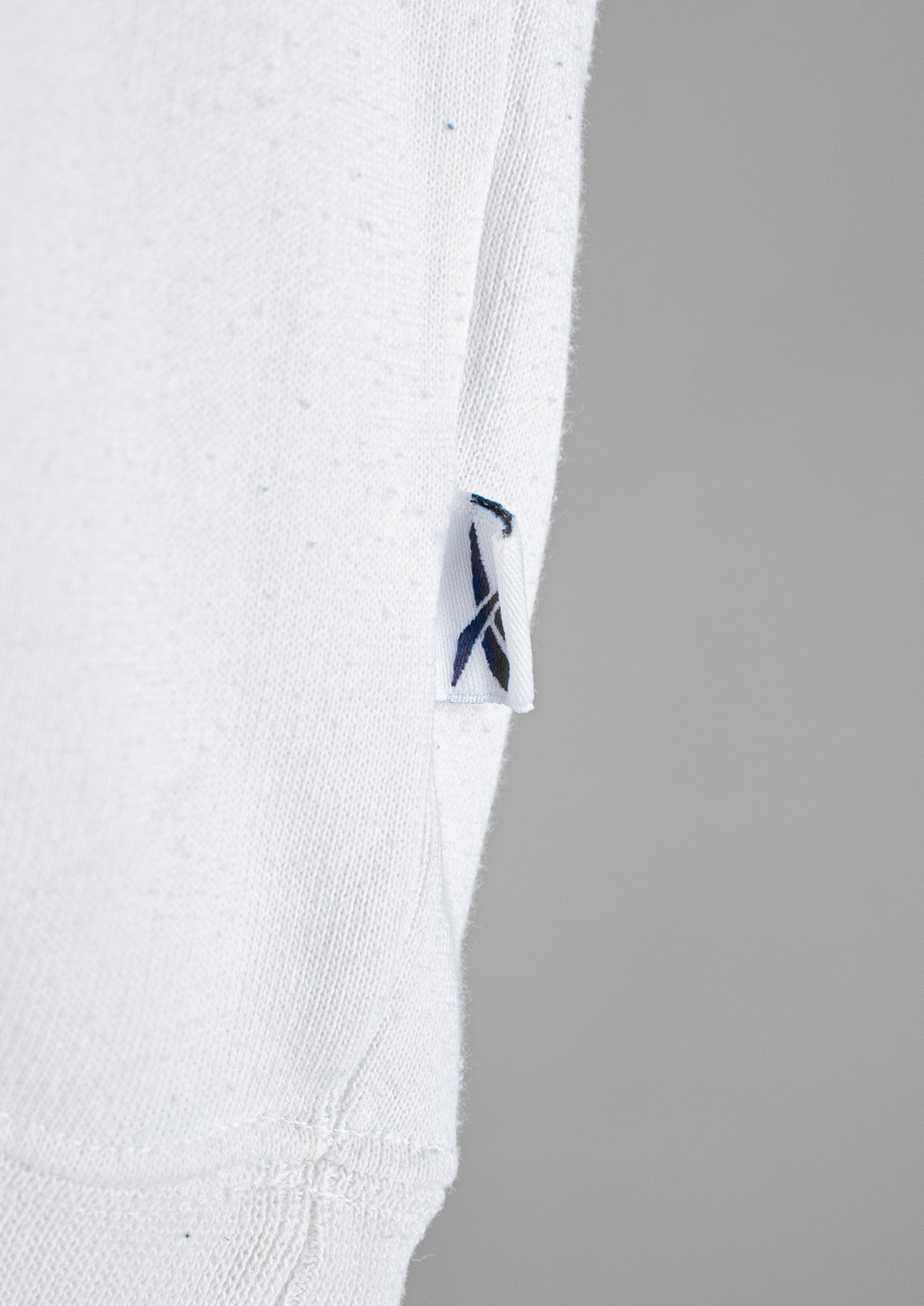 Close-up van de details van een witte Reebok sweater in maat S, met zorgvuldig afgewerkte details voor een sportieve uitstraling.