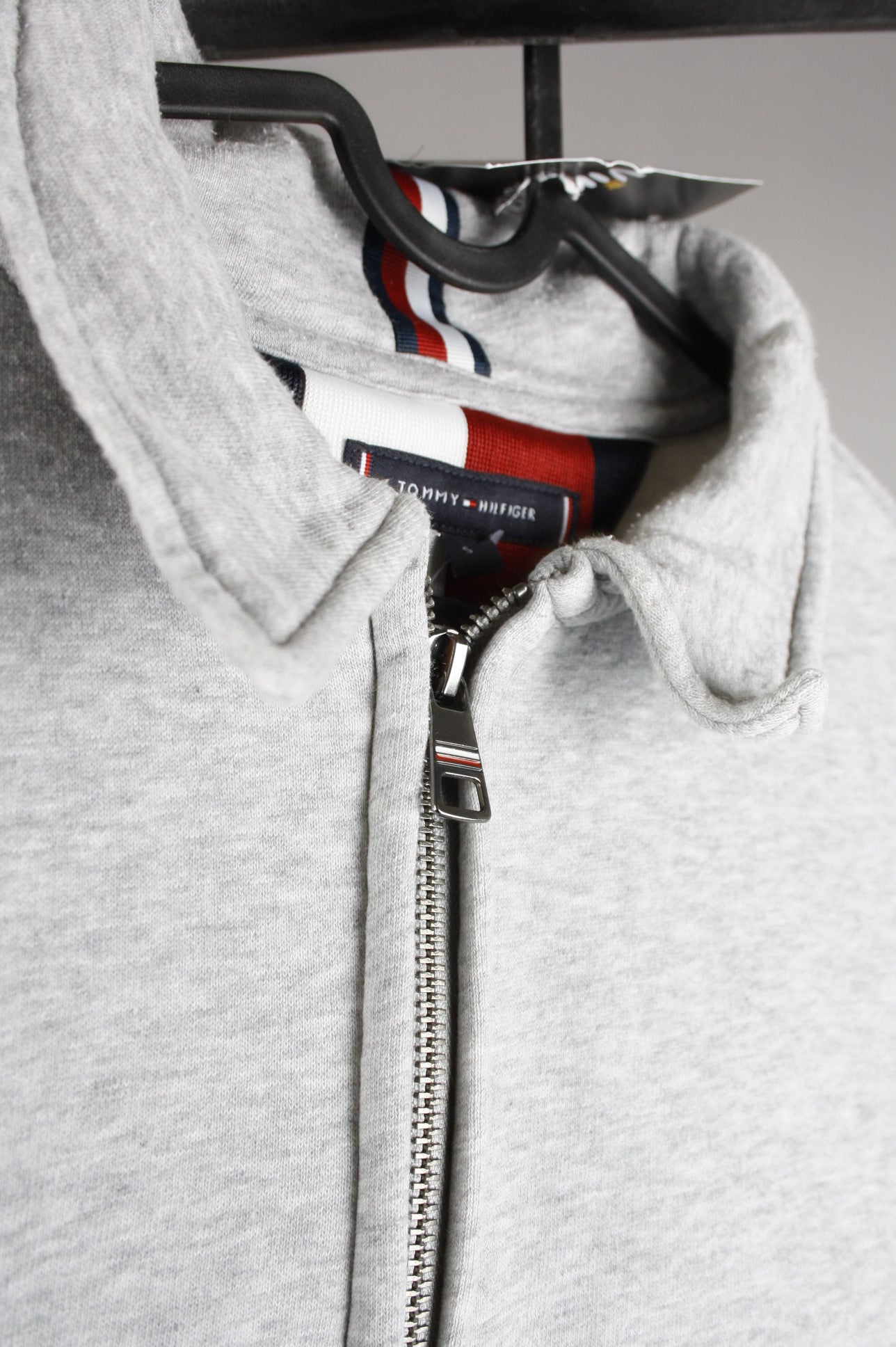 Close-up van de rits van een grijze Tommy Hilfiger quarter zip sweater, met een hoogwaardige metalen afwerking en sportieve uitstraling.