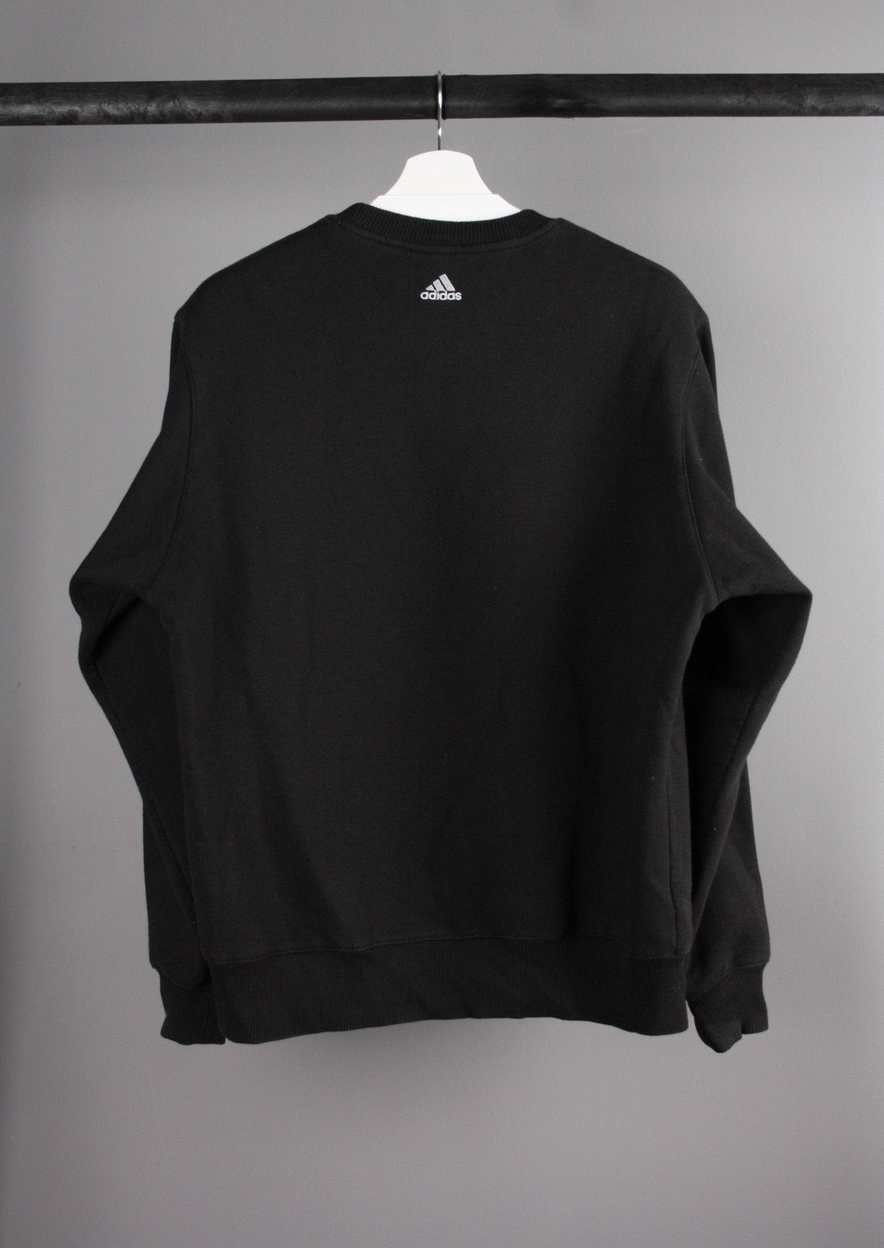 Achterkant van een vintage Adidas sweater met een eenvoudige stijl en een klassieke pasvorm, perfect voor een retro en sportieve look.