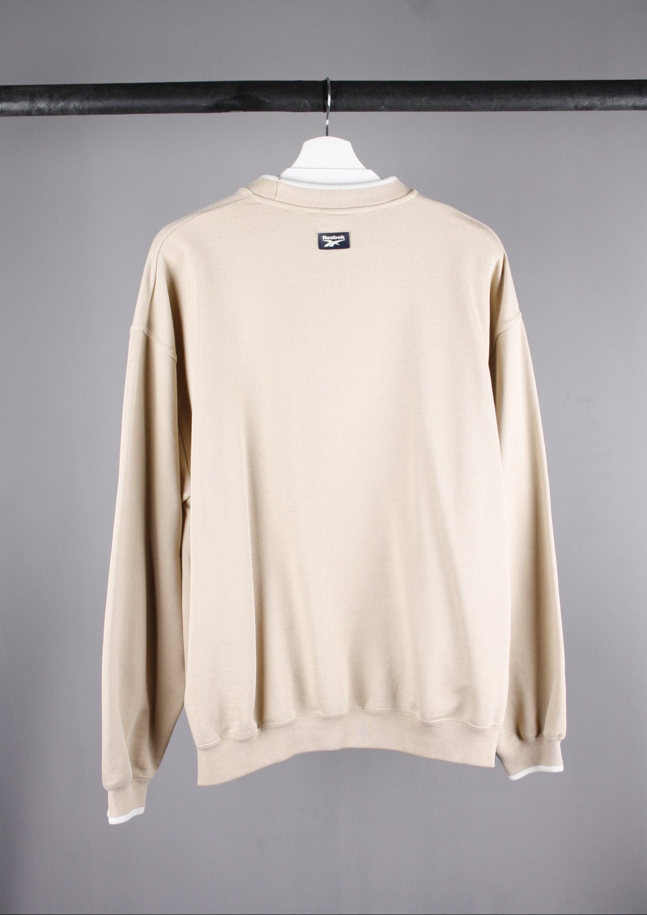 Achterkant van een beige Reebok Athletic Dept sweater in maat S, met een eenvoudige, stijlvolle pasvorm voor dagelijks comfort.
