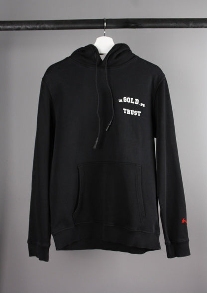 Voorkant van een zwarte 'In Gold We Trust' hoodie met het merklogo op de borst en een capuchon, gemaakt van een zachte en comfortabele stof.
