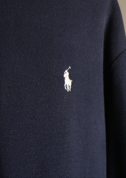 Close-up van het wit geborduurde paardje op de voorkant van een marineblauw Ralph Lauren vest, het herkenbare logo van het merk.