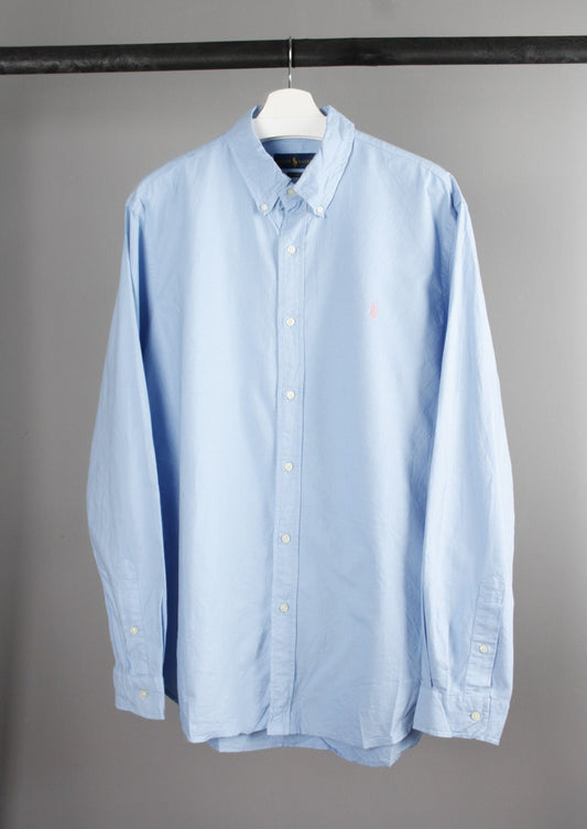 Voorkant van een lichtblauwe Ralph Lauren blouse met een roze geborduurd paardje op de borst, gemaakt van een lichtgewicht katoenen stof.