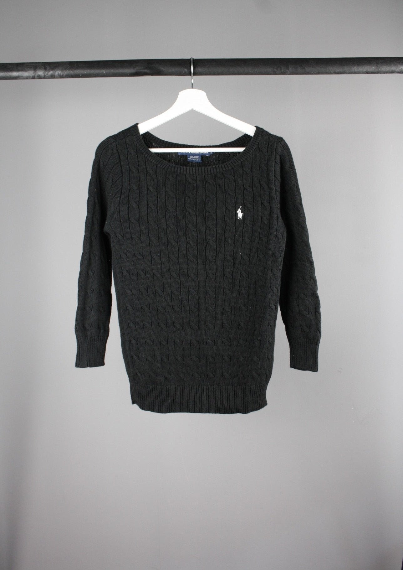 Voorkant van een zwarte Ralph Lauren cable knit sweater met een wit paardje op de borst, gebreid van hoogwaardige wol voor een klassieke en elegante uitstraling.