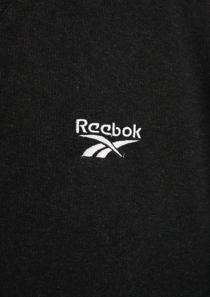 Close-up van het wit geborduurde logo linksboven op de voorkant van een zwarte Reebok sweater in maat L