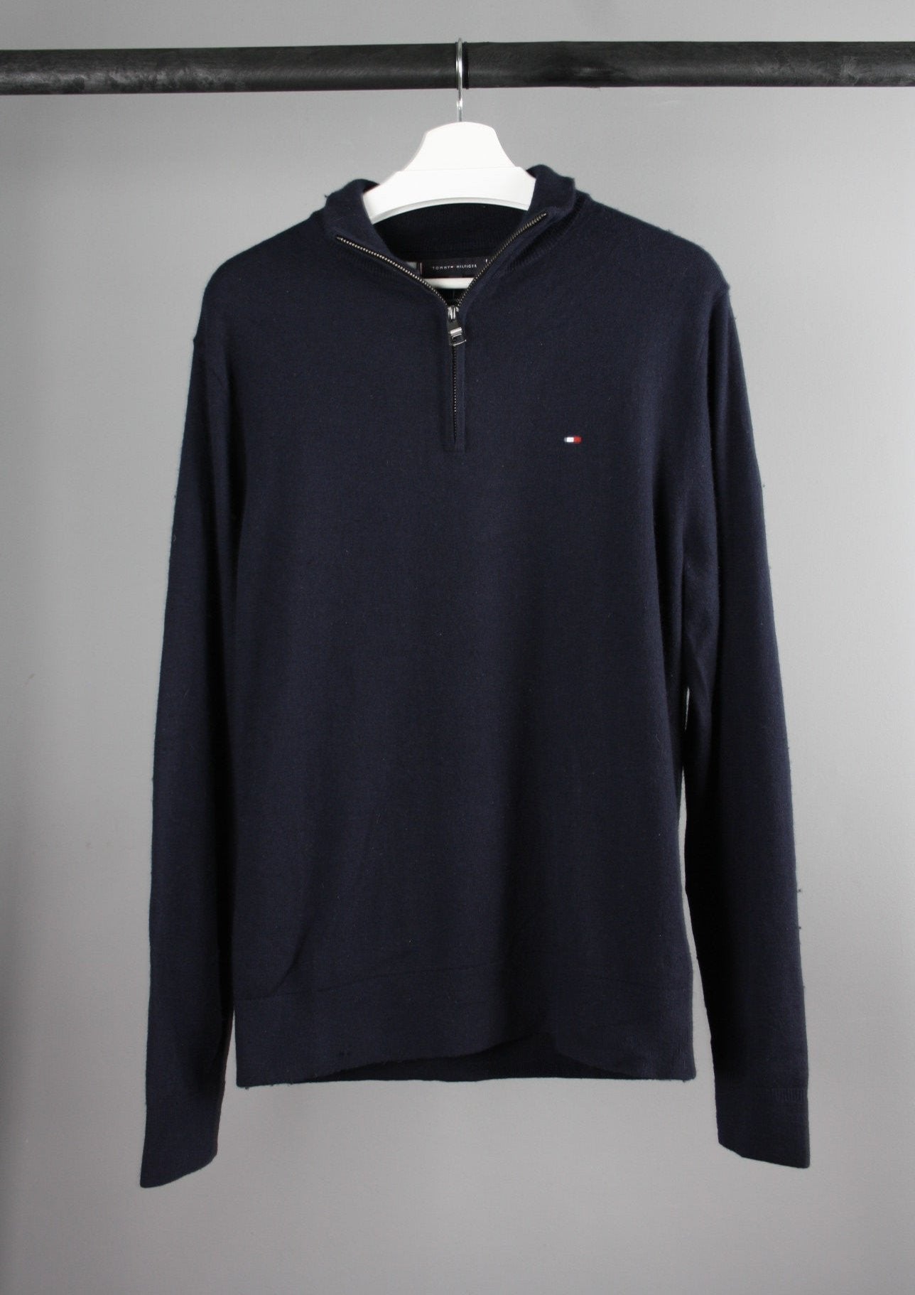 Voorkant van een marineblauwe Tommy Hilfiger quarter-zip sweater met opstaande kraag en het merklogo op de borst, gemaakt van zachte en ademende stof.