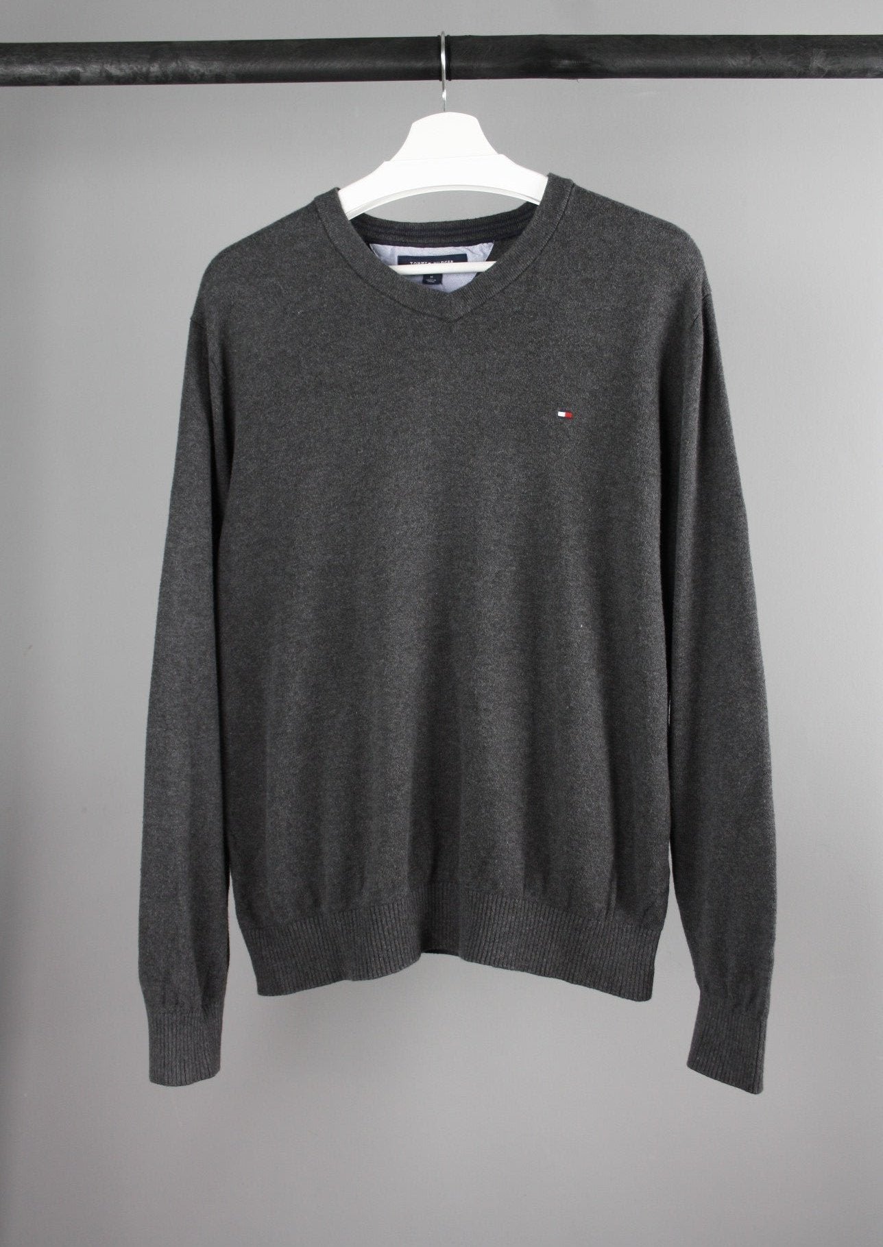 Voorkant van een grijze Tommy Hilfiger sweater met ronde hals en het Tommy Hilfiger-logo op de borst, gemaakt van zachte en comfortabele stof.