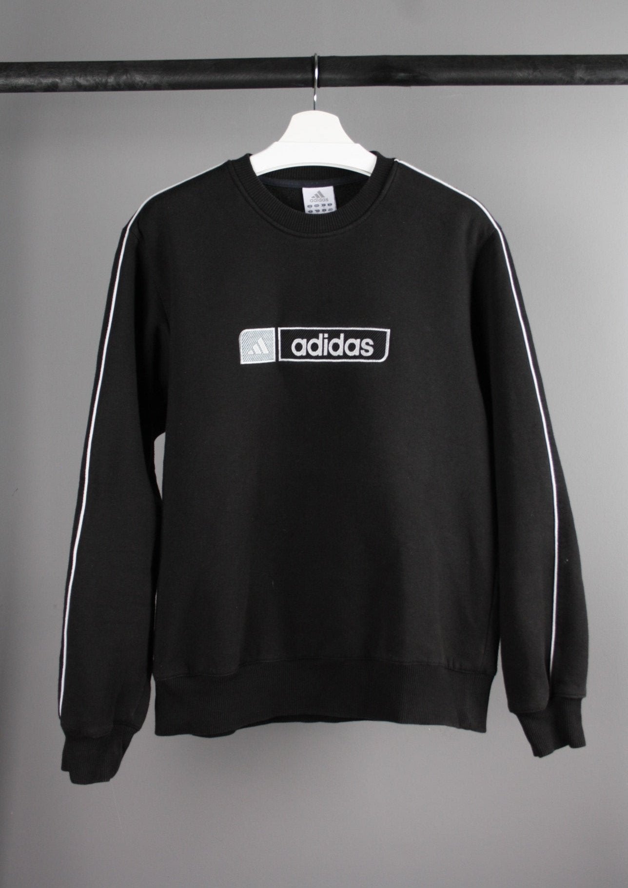 Voorkant van een vintage Adidas sweater met een groot, geborduurd logo op de borst, gemaakt van een comfortabele stof met een retro uitstraling.