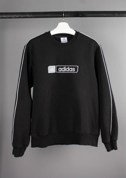 Voorkant van een vintage Adidas sweater met een groot, geborduurd logo op de borst, gemaakt van een comfortabele stof met een retro uitstraling.